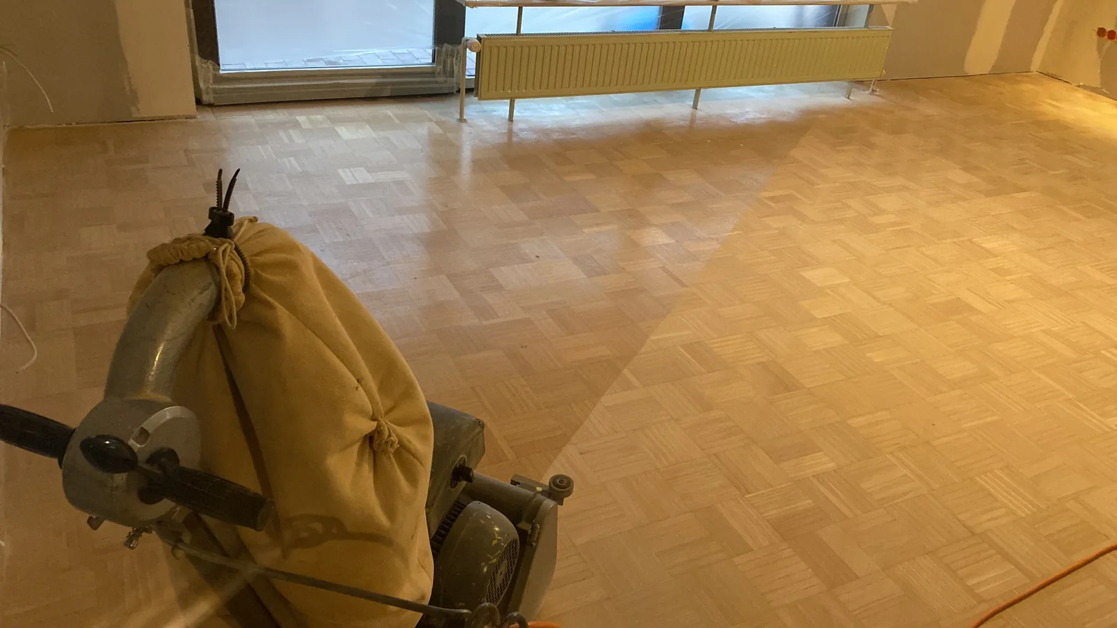 Parkettboden mit Schleifmaschine während der Aufarbeitung
